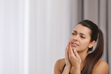 Photo of Young woman with sensitive teeth indoors. Space for text