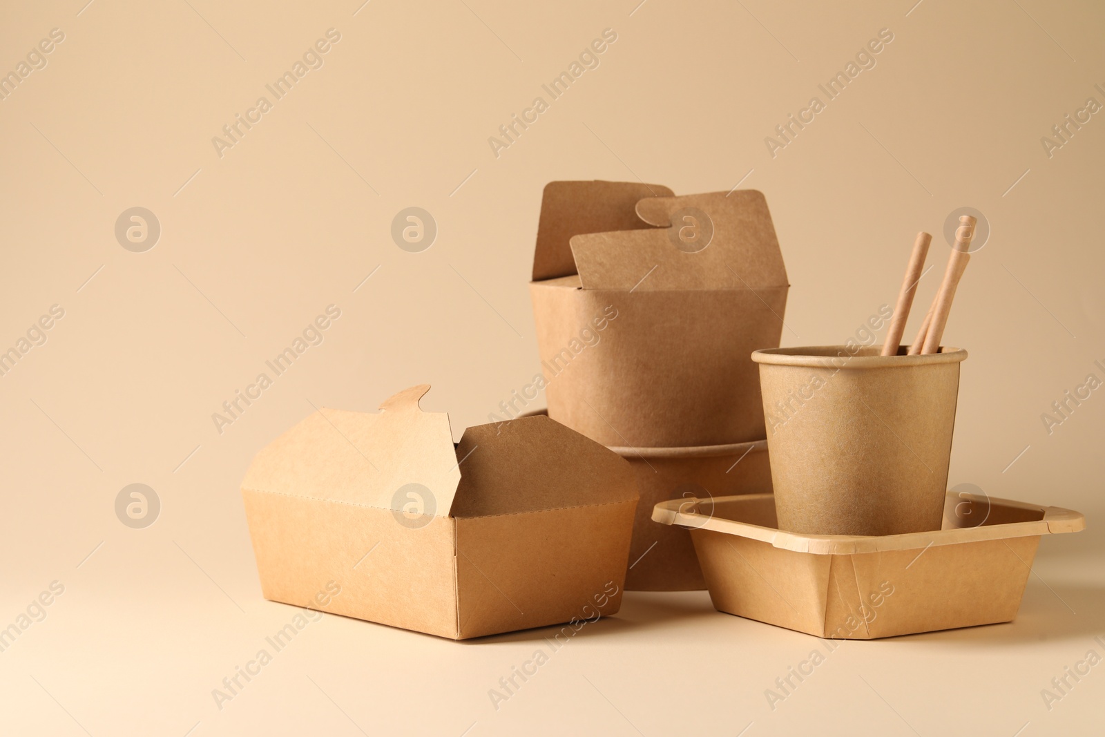 Photo of Eco friendly food packaging. Paper containers and tableware on beige background, space for text