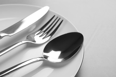 Photo of Plate with cutlery on light grey table, closeup
