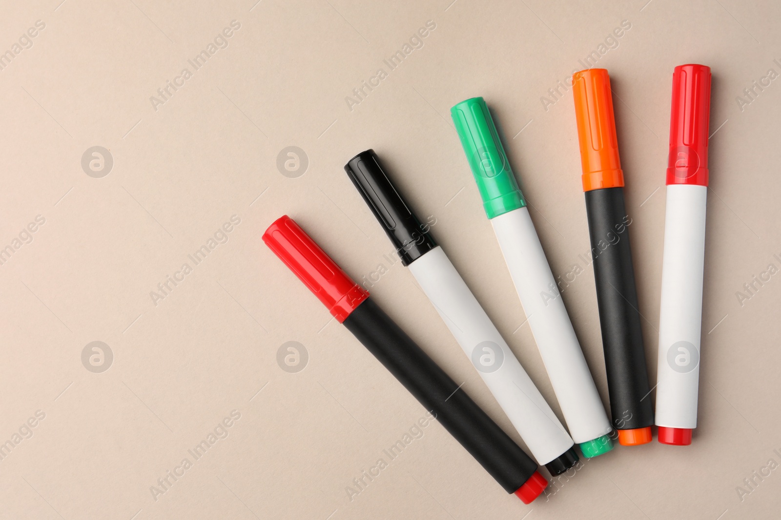 Photo of Bright color markers on beige background, flat lay. Space for text