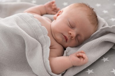 Photo of Cute little baby under soft plaid sleeping on bed