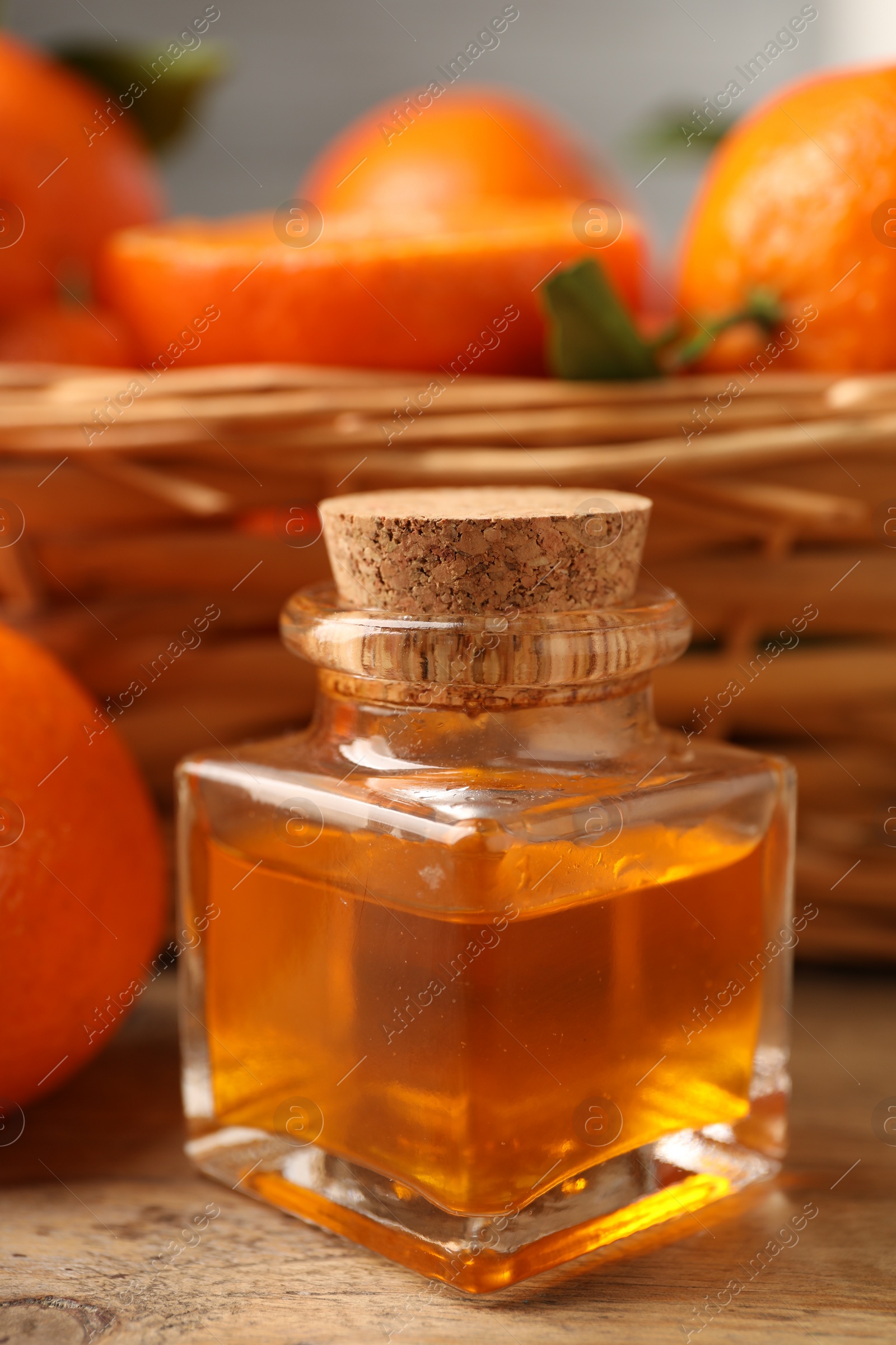 Photo of Bottle of tangerine essential oil and fresh fruits on wooden table, closeup