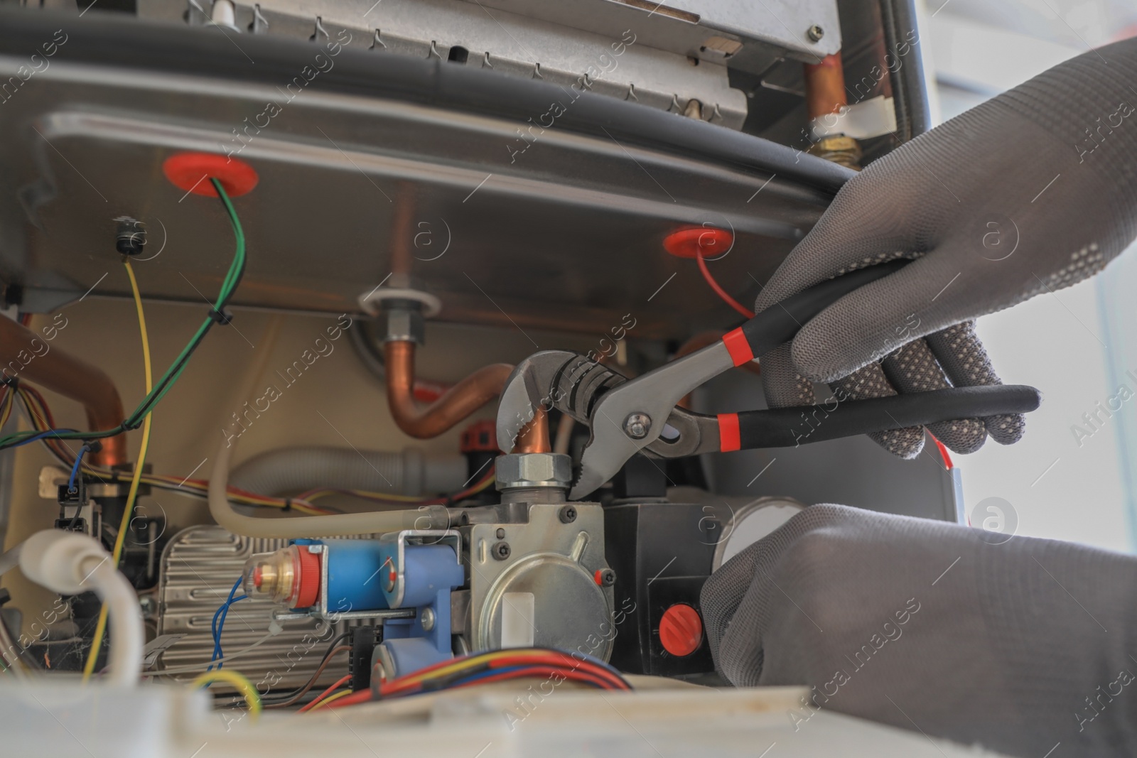 Photo of Man repairing gas boiler with waterpump plier, closeup