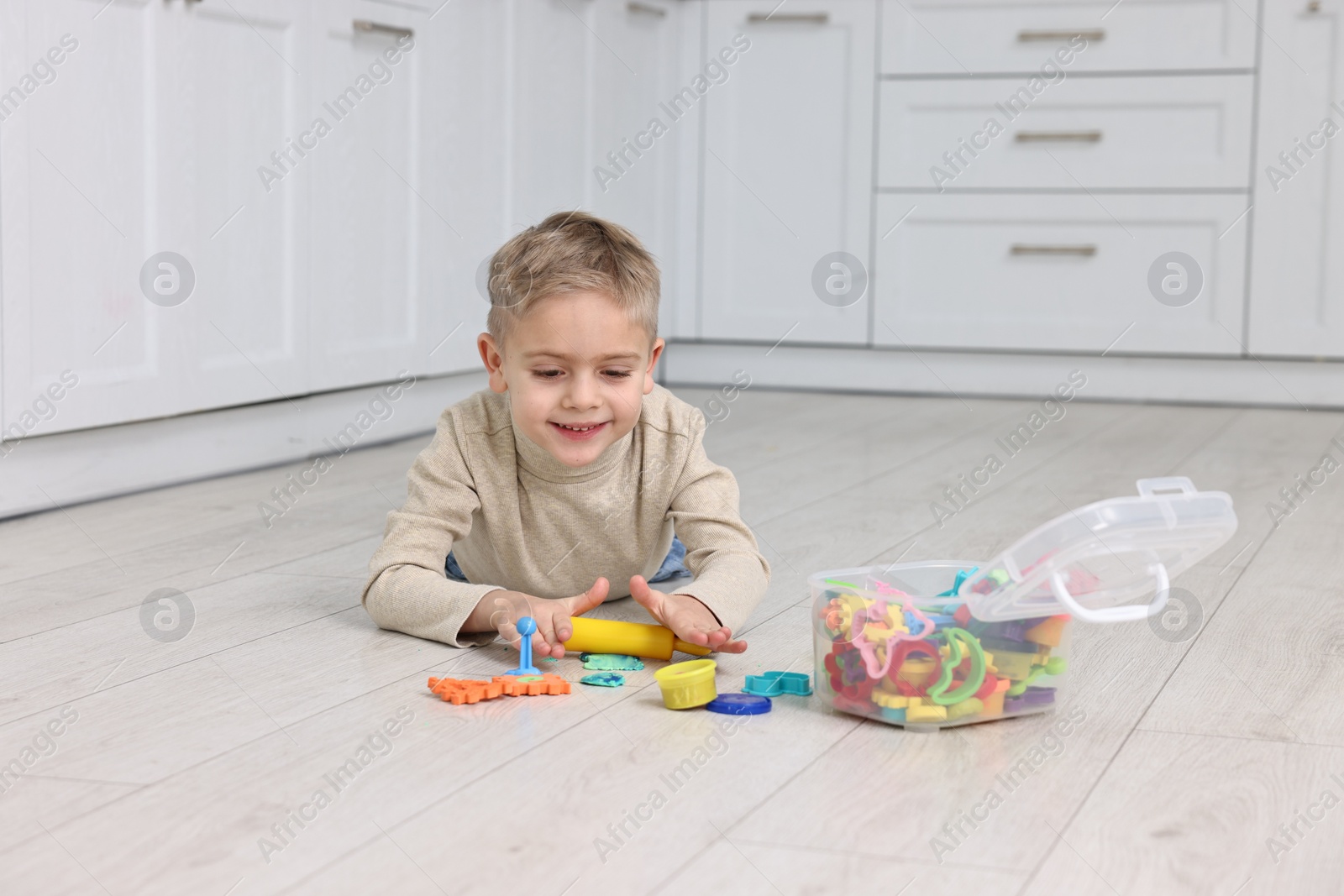 Photo of Cute little boy playing on warm floor in kitchen. Heating system