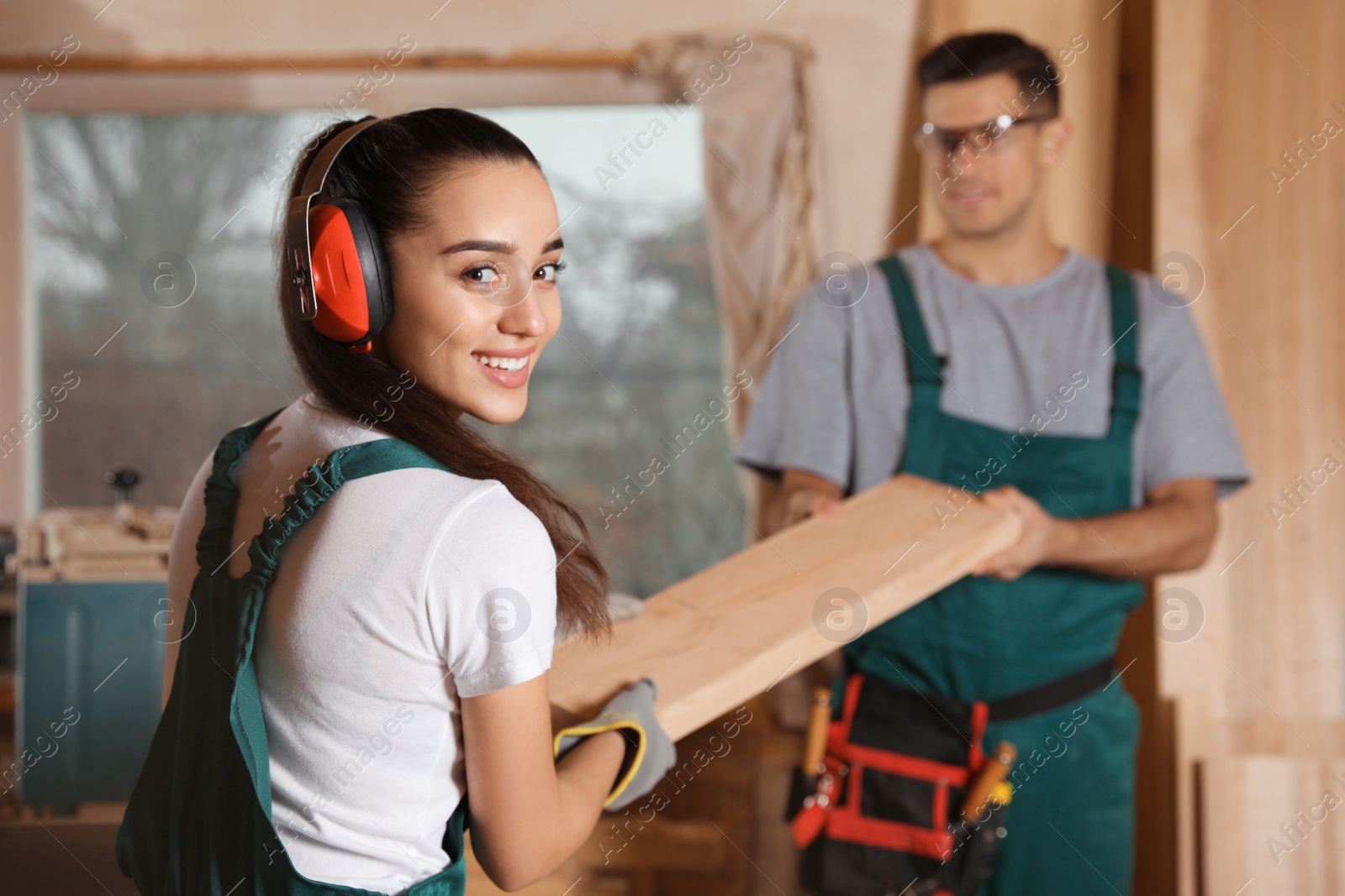 Photo of Professional carpenters with wooden plank in workshop