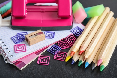 Photo of Different colorful stationery on chalkboard surface. Back to school