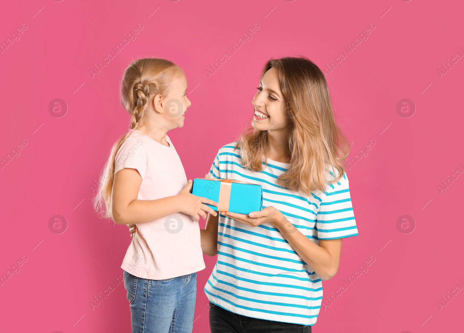 Photo of Little daughter congratulating her mom on pink background. Happy Mother's Day