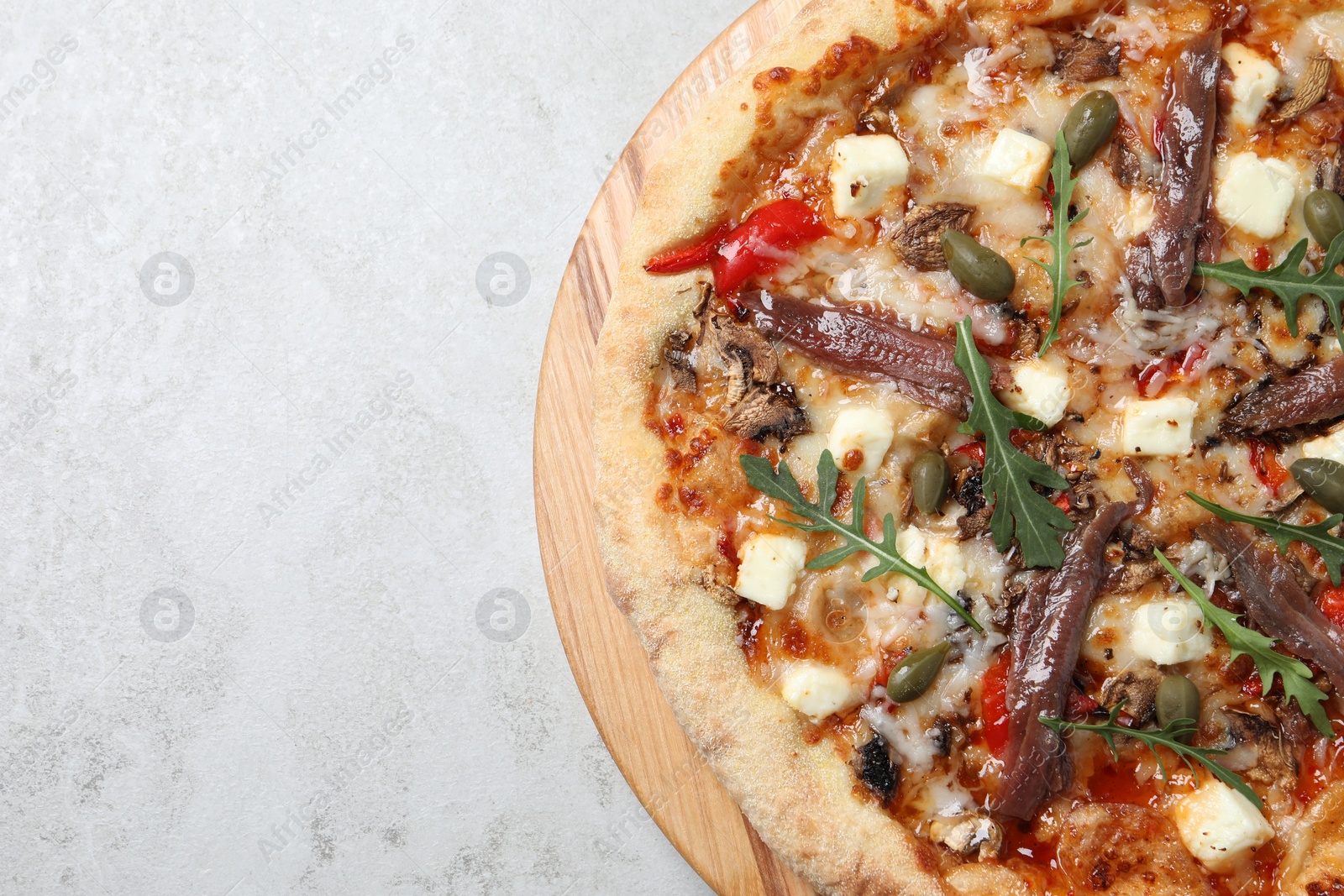 Photo of Tasty pizza with anchovies, arugula and olives on grey table, top view. Space for text