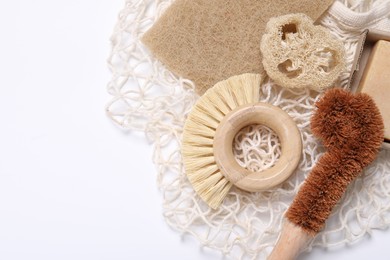 Photo of Cleaning brushes, sponge, loofah and soap bar on white table, top view. Space for text