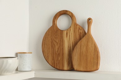 Photo of Wooden cutting boards, container and bowls on white shelf