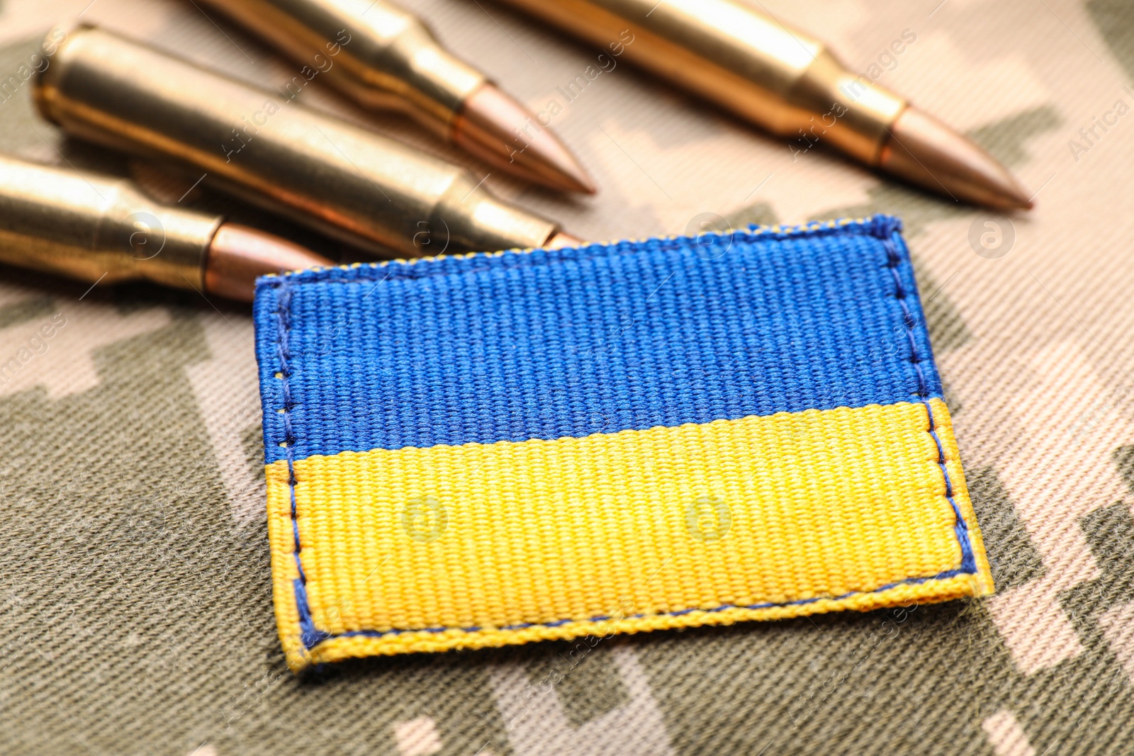 Photo of Military patch and bullets on pixel Ukrainian camouflage, closeup