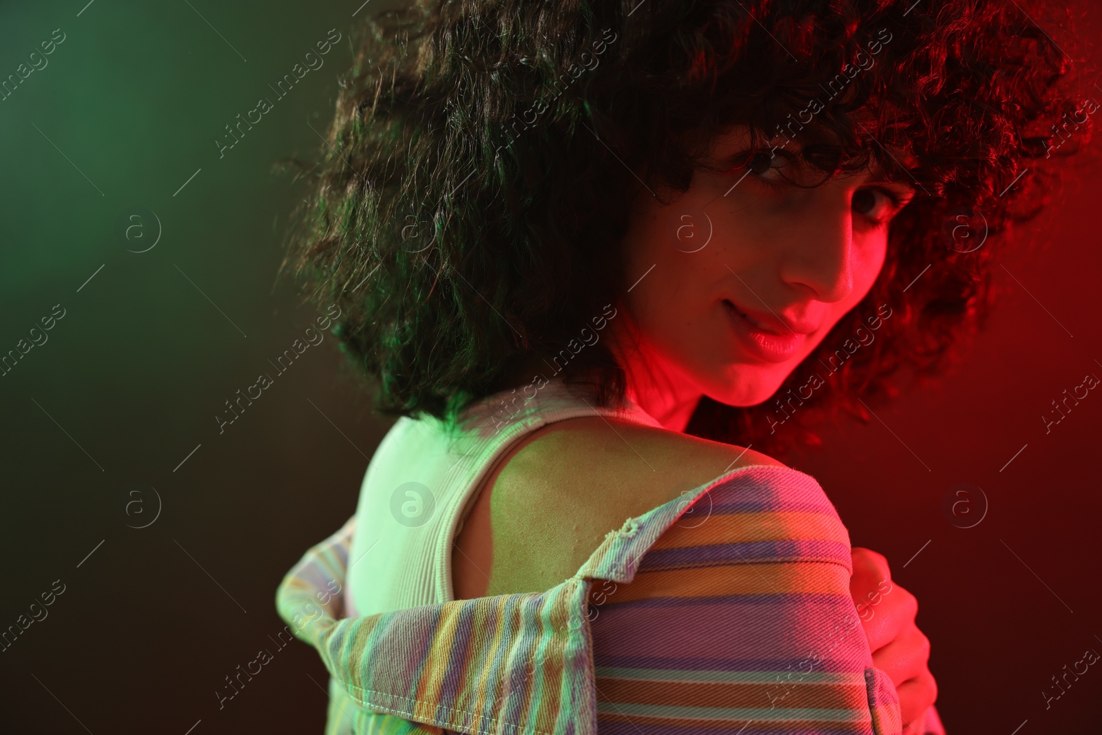 Photo of Beautiful young woman posing on color background in neon lights