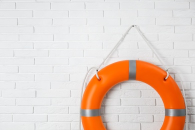 Photo of Orange lifebuoy and space for text on white brick wall. Rescue equipment