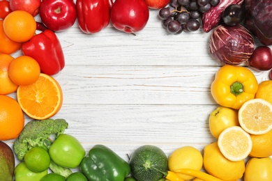 Photo of Rainbow frame made of fresh fruits and vegetables on wooden background