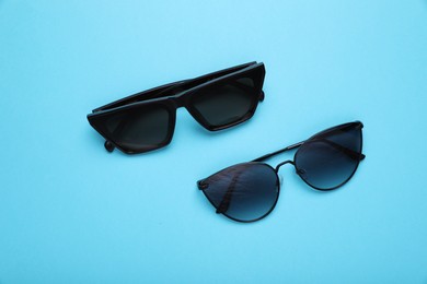 Stylish sunglasses on light blue background, flat lay