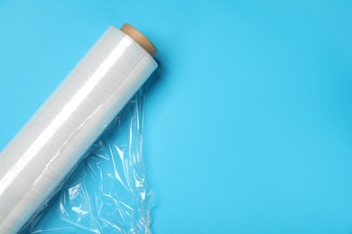 Photo of Roll of transparent stretch wrap on turquoise background, top view. Space for text