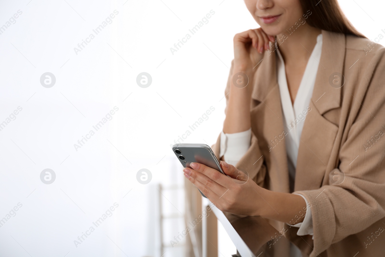 Photo of Young woman using modern smartphone indoors, closeup. Space for text