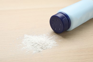 Photo of Bottle and scattered dusting powder on wooden background. Baby cosmetic product