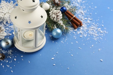 Photo of Christmas lantern with burning candle and festive decor on blue background