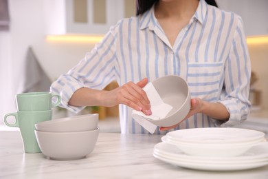 Photo of Woman wiping bowl with paper towel in kitchen, closeup