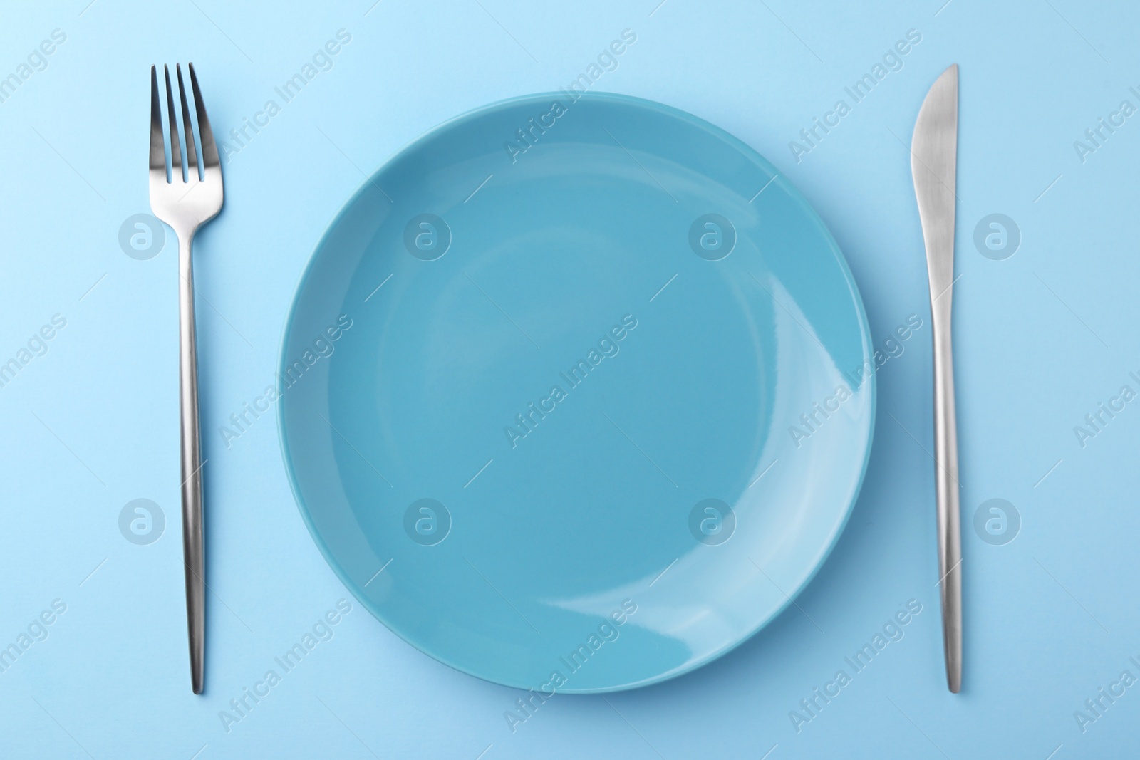 Photo of Setting with stylish cutlery on light blue table, top view