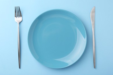 Setting with stylish cutlery on light blue table, top view