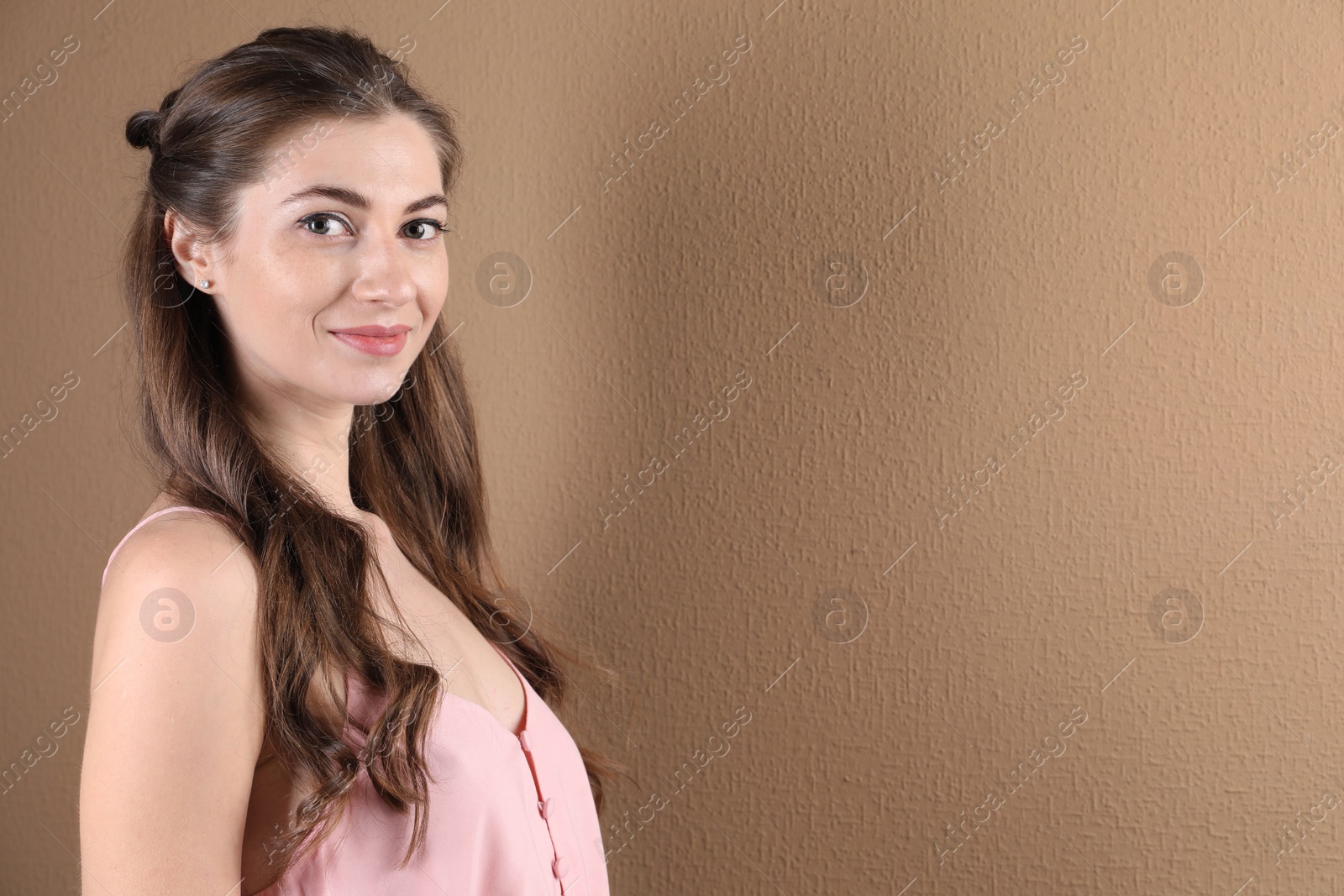 Photo of Woman with wavy hair on light brown background. Space for text