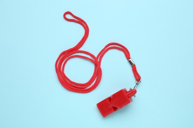 Photo of One red whistle with cord on light blue background, top view