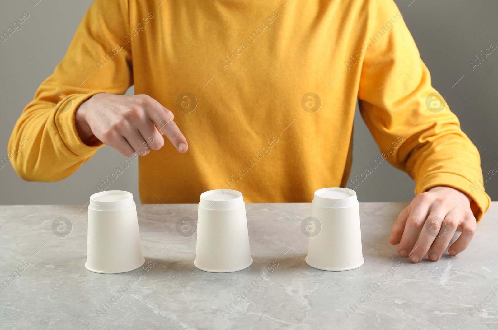 Photo of Man playing shell game at light marble table, closeup