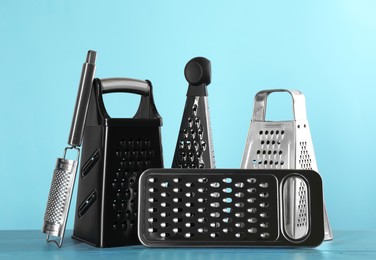 Photo of Different modern graters on light blue wooden table