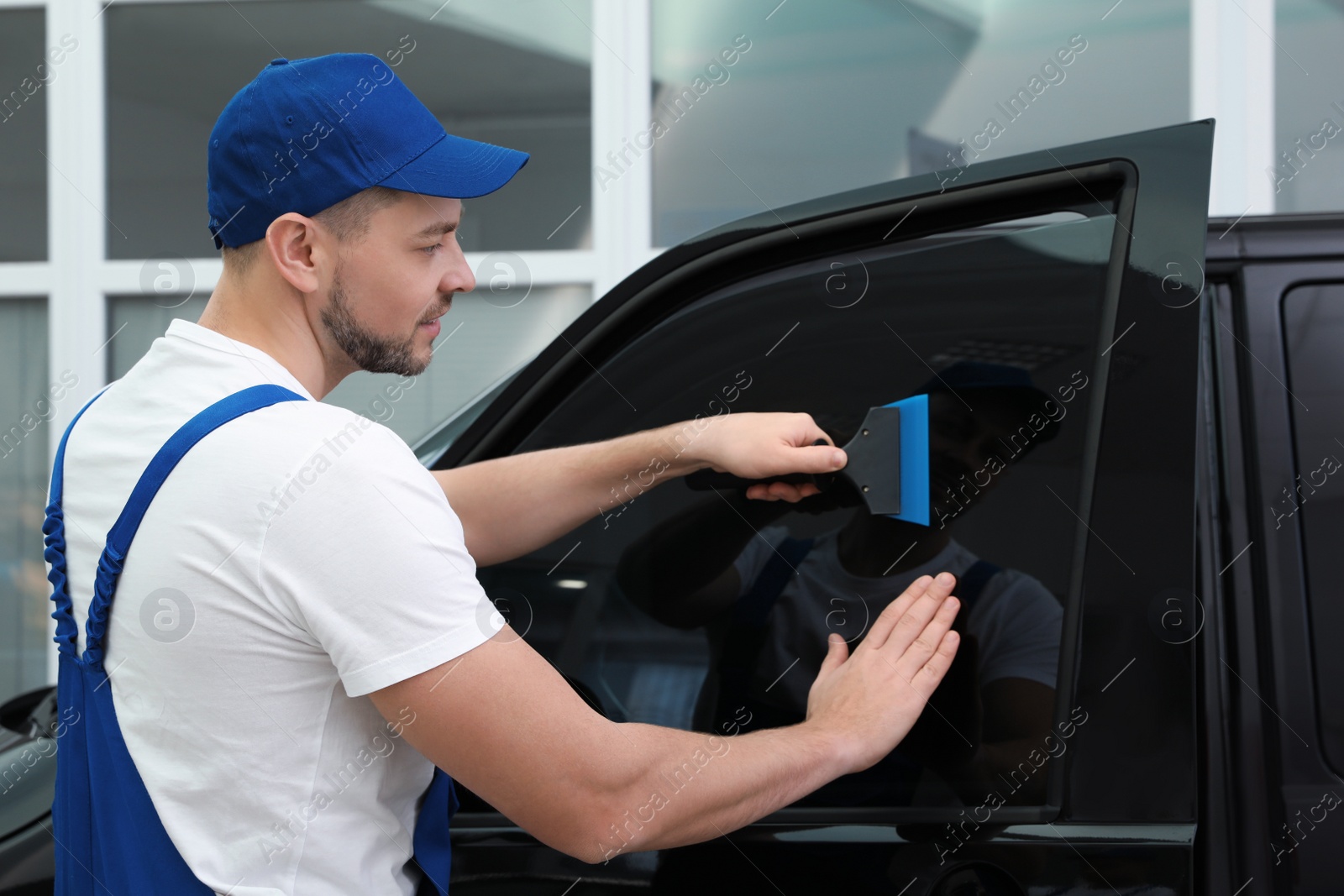 Photo of Worker tinting car window with foil in workshop