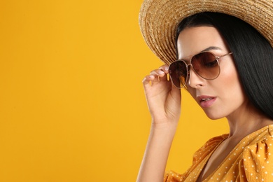 Photo of Beautiful woman wearing sunglasses on yellow background. Space for text