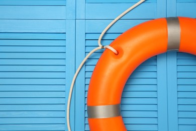 Photo of Orange lifebuoy on turquoise wooden background, space for text. Rescue equipment