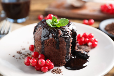 Photo of Delicious warm chocolate lava cake with mint and berries on plate, closeup