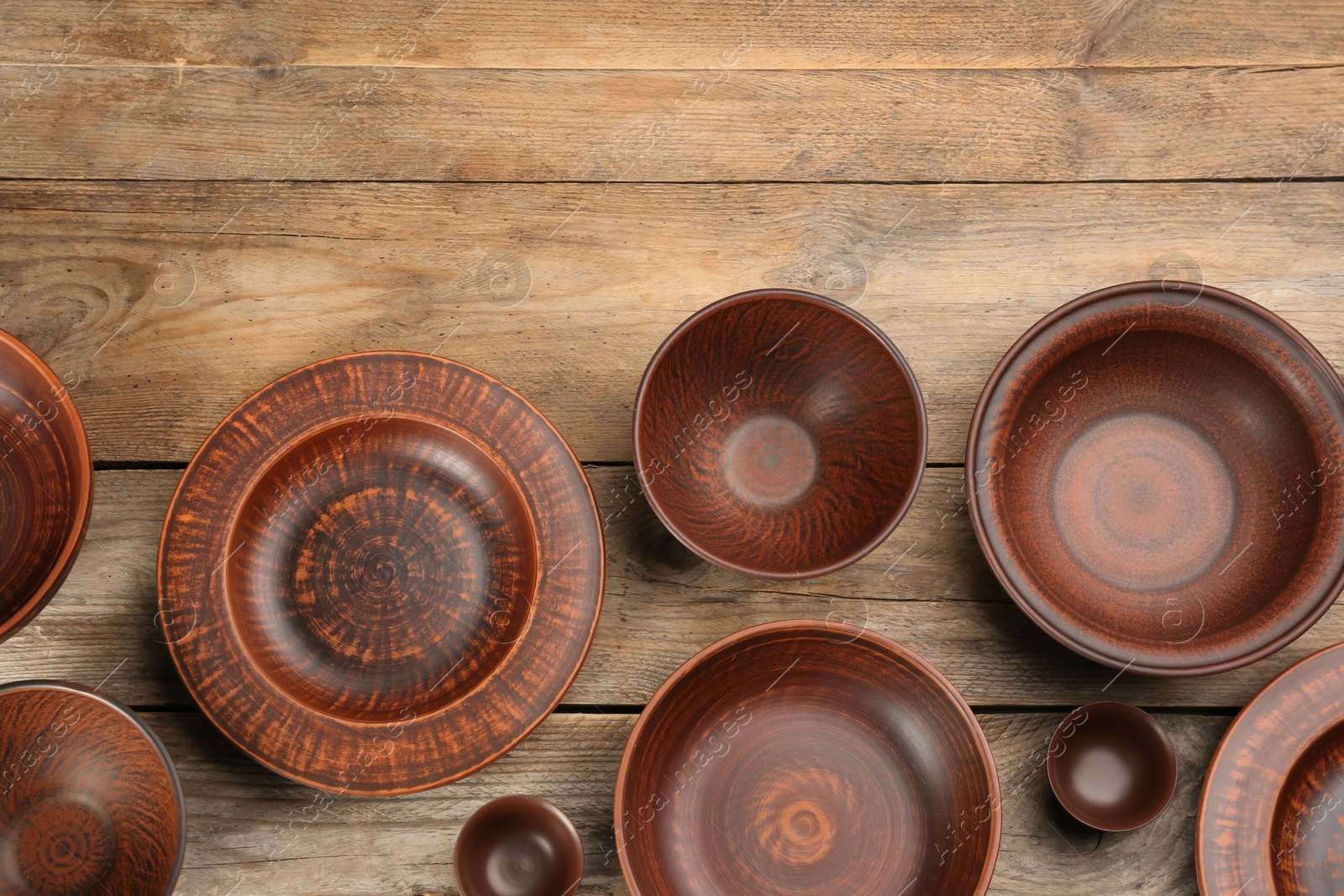 Photo of Set of clay utensils on wooden table, flat lay