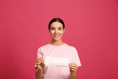 Photo of Young woman with menstrual pad on bright pink background