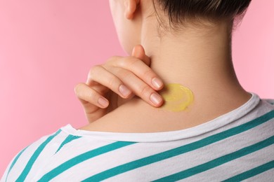 Photo of Woman applying ointment onto her neck on pink background, closeup