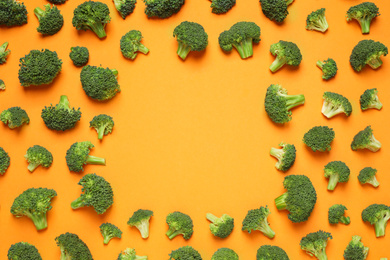 Photo of Fresh tasty broccoli on orange background, flat lay. Space for text