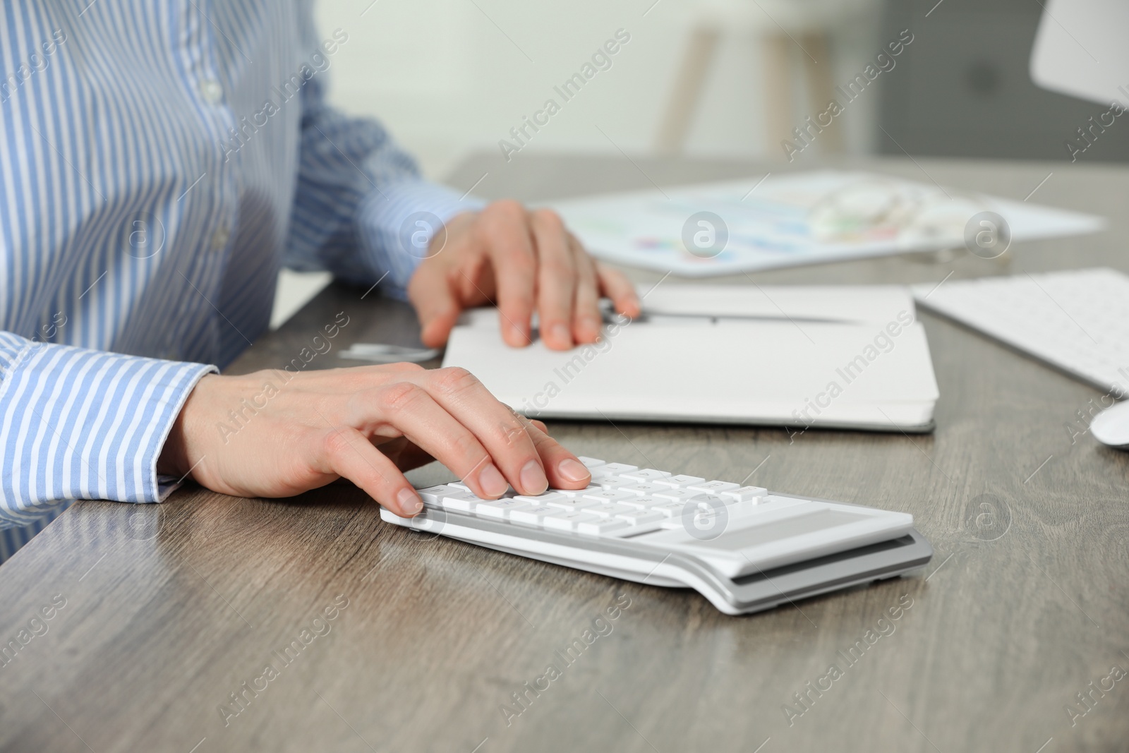 Photo of Professional accountant using calculator at wooden desk in office, closeup