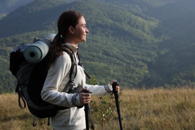 Photo of Tourist with backpack and trekking poles hiking through mountains, space for text