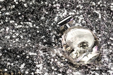 Photo of Luxury perfume in bottle on fabric with silver sequins