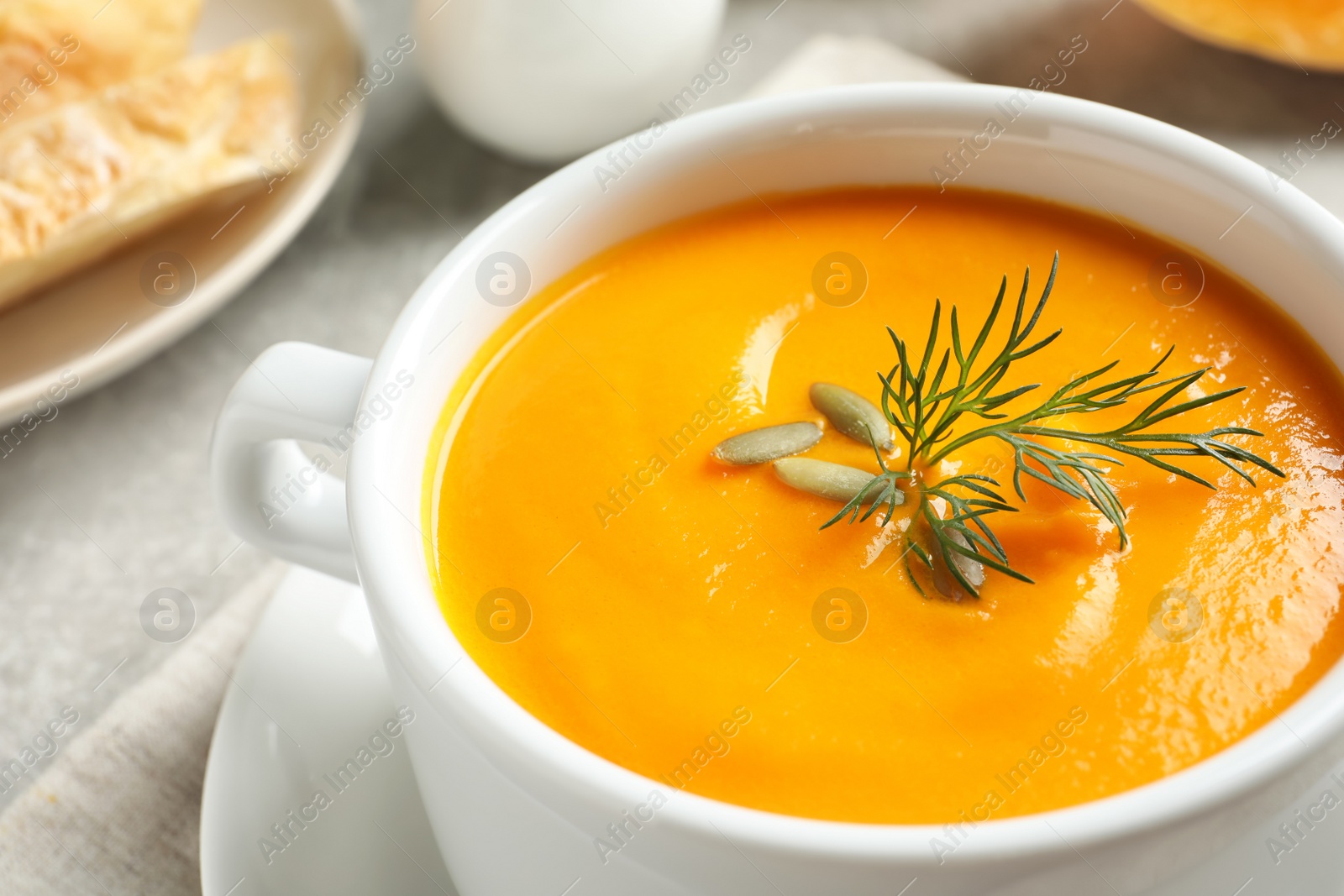 Photo of Delicious pumpkin cream soup in bowl on table, closeup