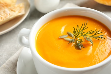 Photo of Delicious pumpkin cream soup in bowl on table, closeup