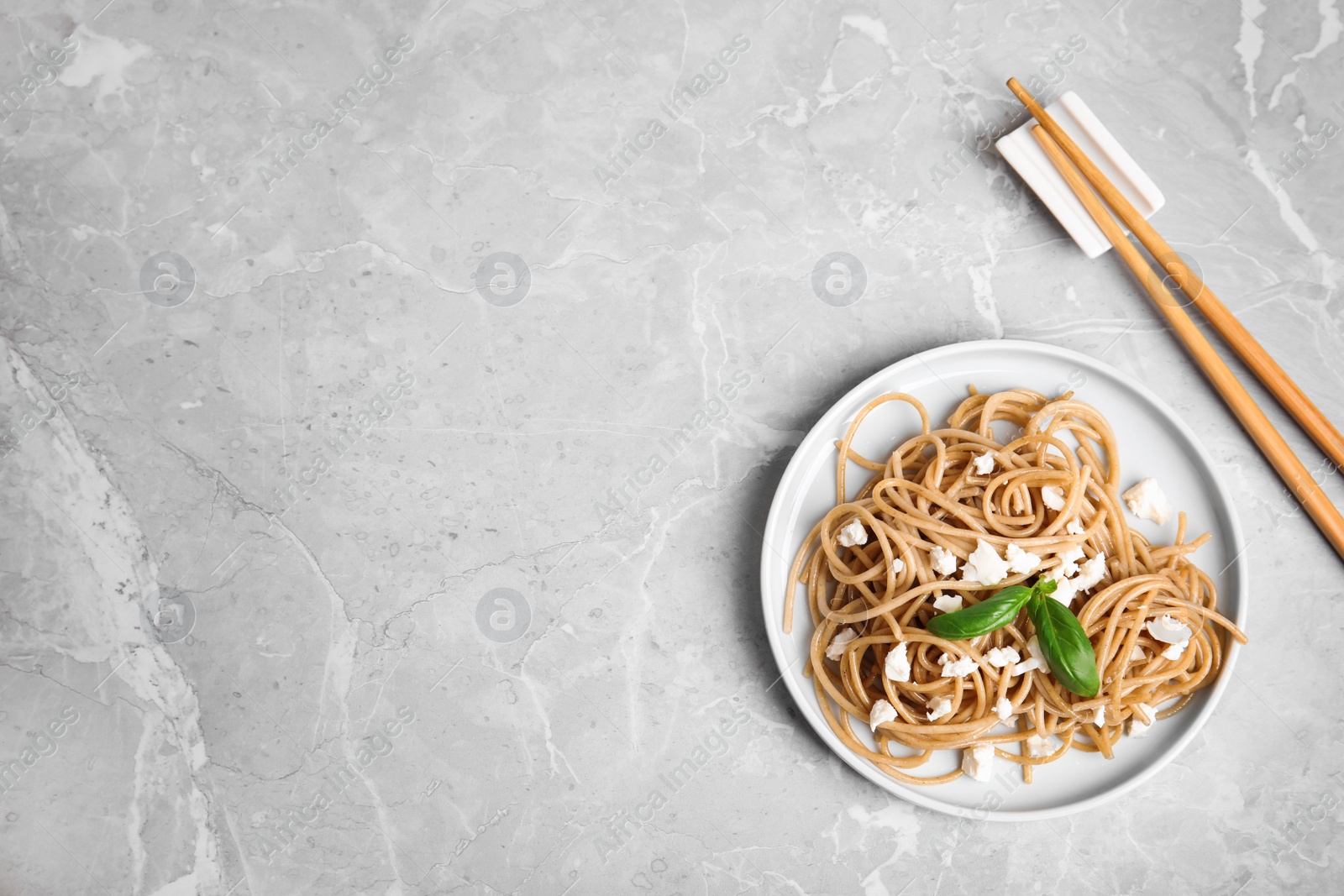 Photo of Tasty buckwheat noodles with chopsticks on light grey table, flat lay. Space for text