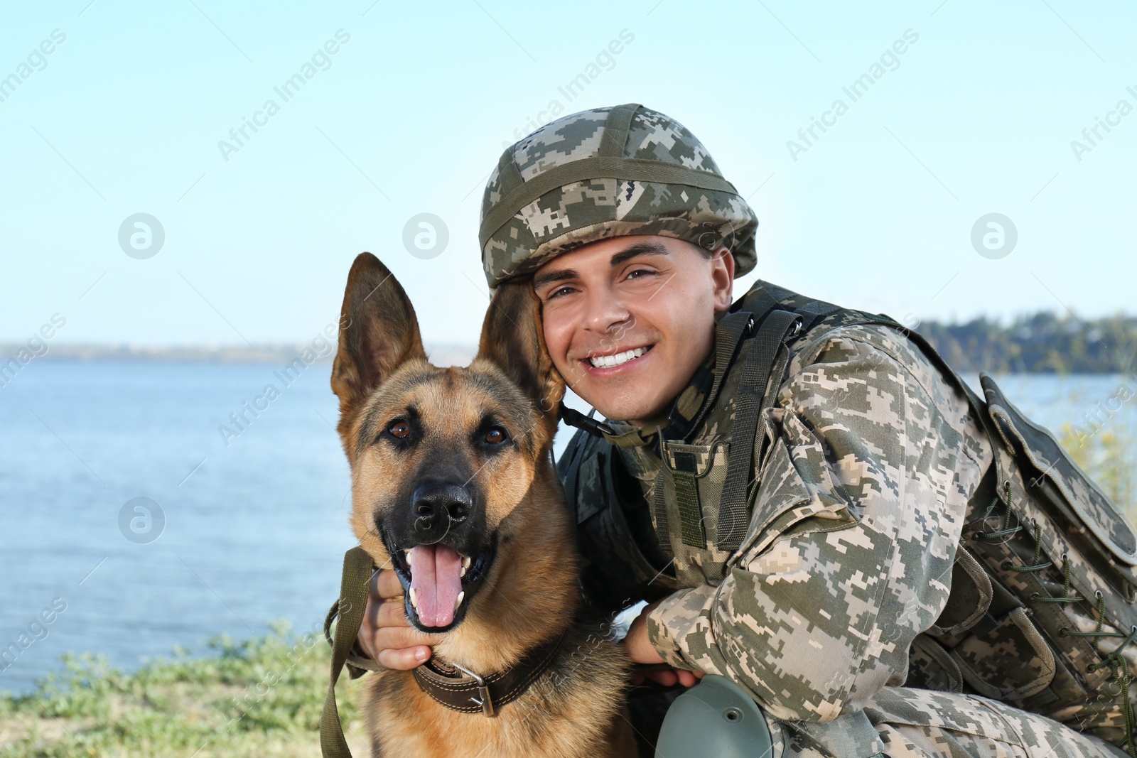 Photo of Man in military uniform with German shepherd dog near river