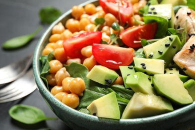 Photo of Delicious avocado salad with chickpea on black table, closeup