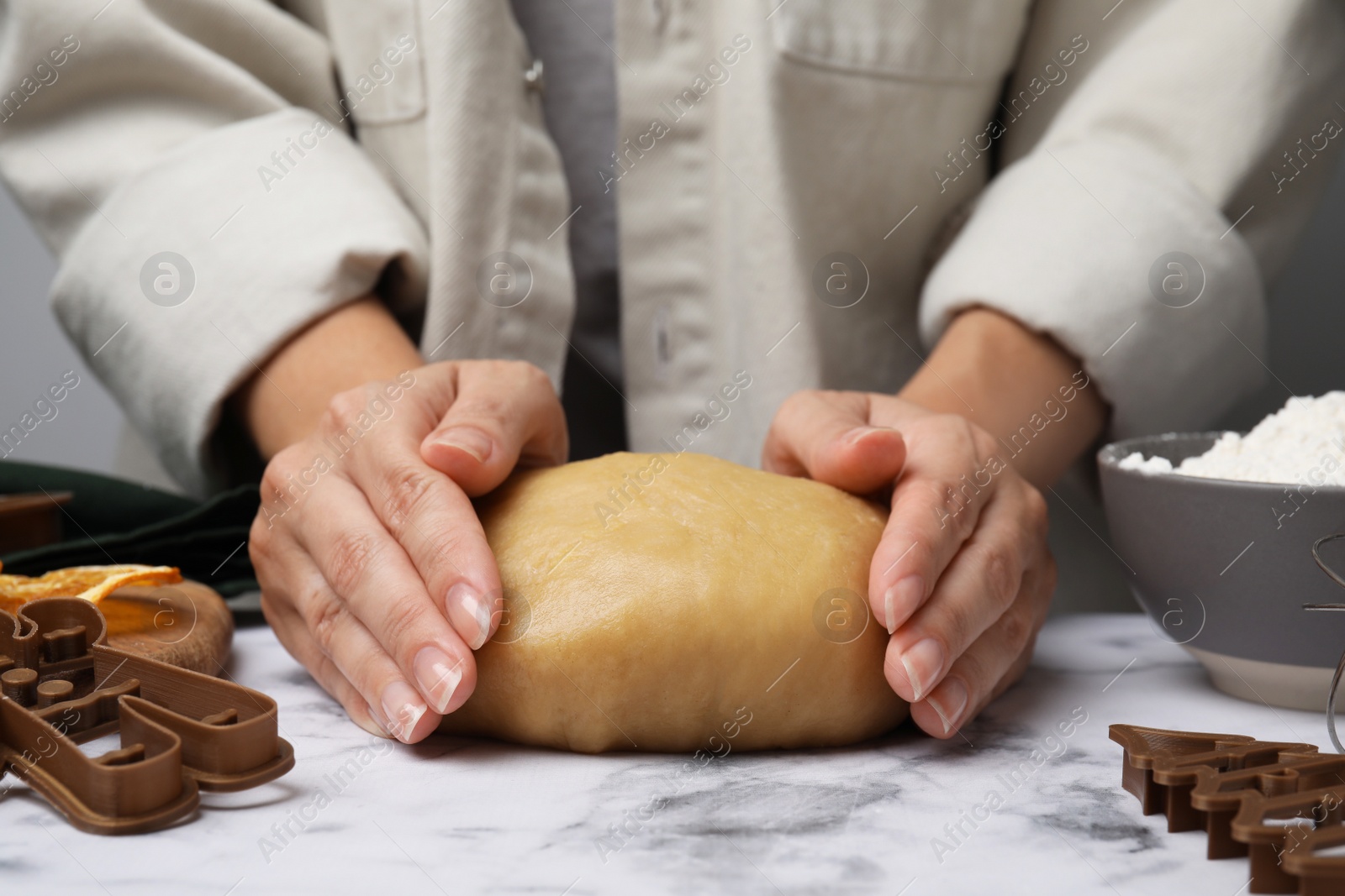 Photo of Woman kneading dough for cookies at white marble table, closeup