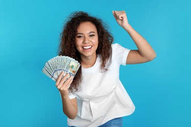 Young African-American woman with money on color background