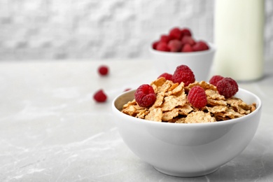 Photo of Bowl with cornflakes and raspberries on gray table. Whole grain cereal for breakfast