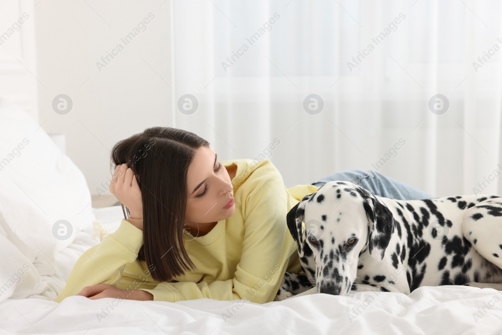 Photo of Beautiful woman with her adorable Dalmatian dog on bed at home. Lovely pet